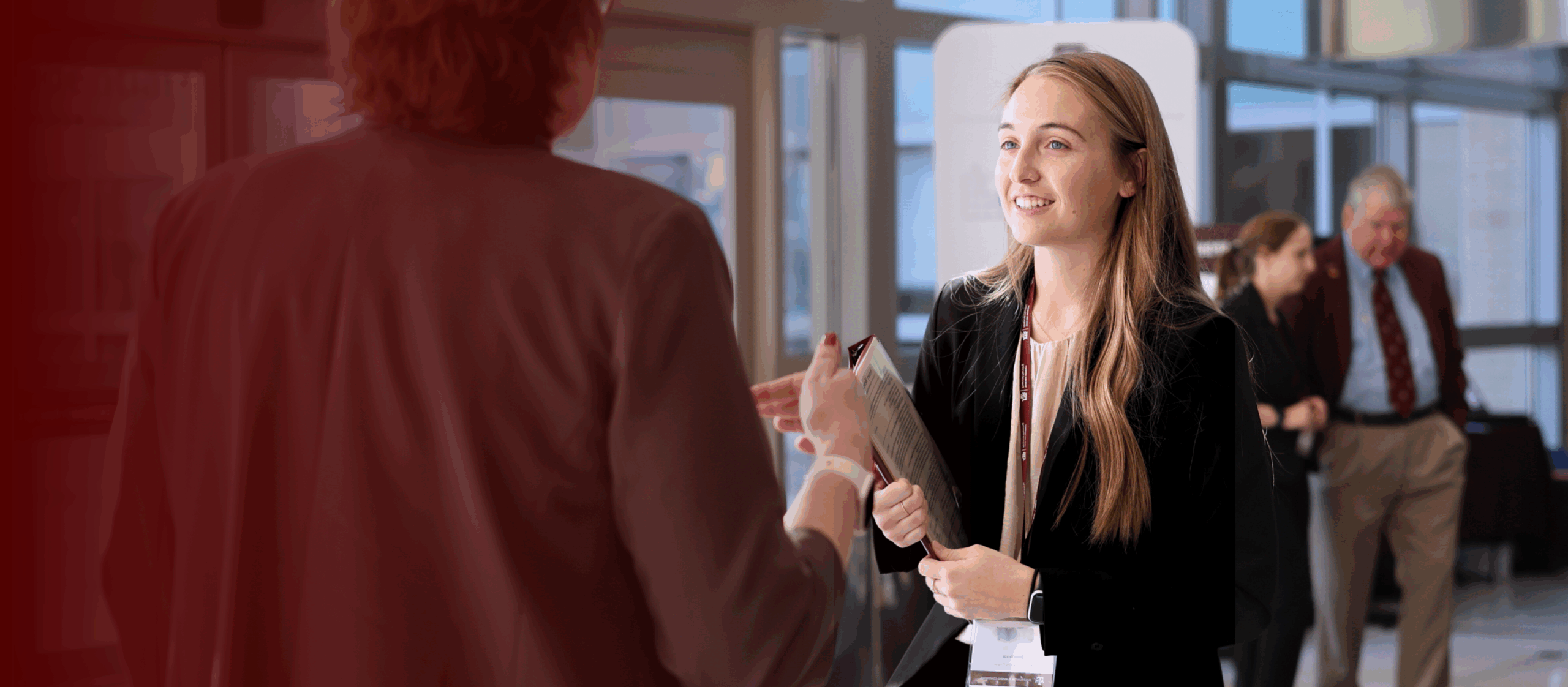 maroon blended background over color photo of female undergraduate financial planning student speaking to professor