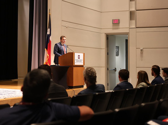 Speaker addressing audience from a podium during the Texas A&M Financial Planning Conference.