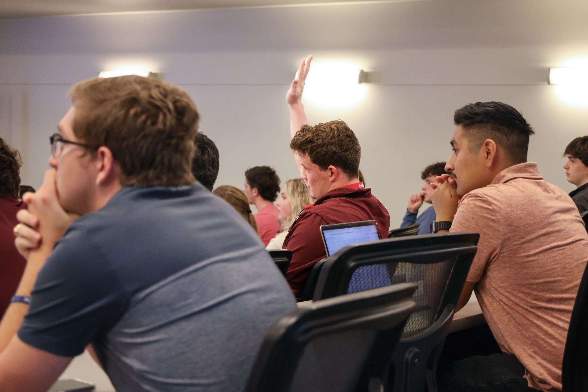 Financial Planning students attending lecture while one student raises hand to ask a question