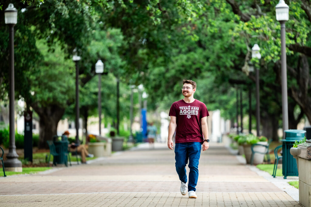 A smiling student walks down Military Walk