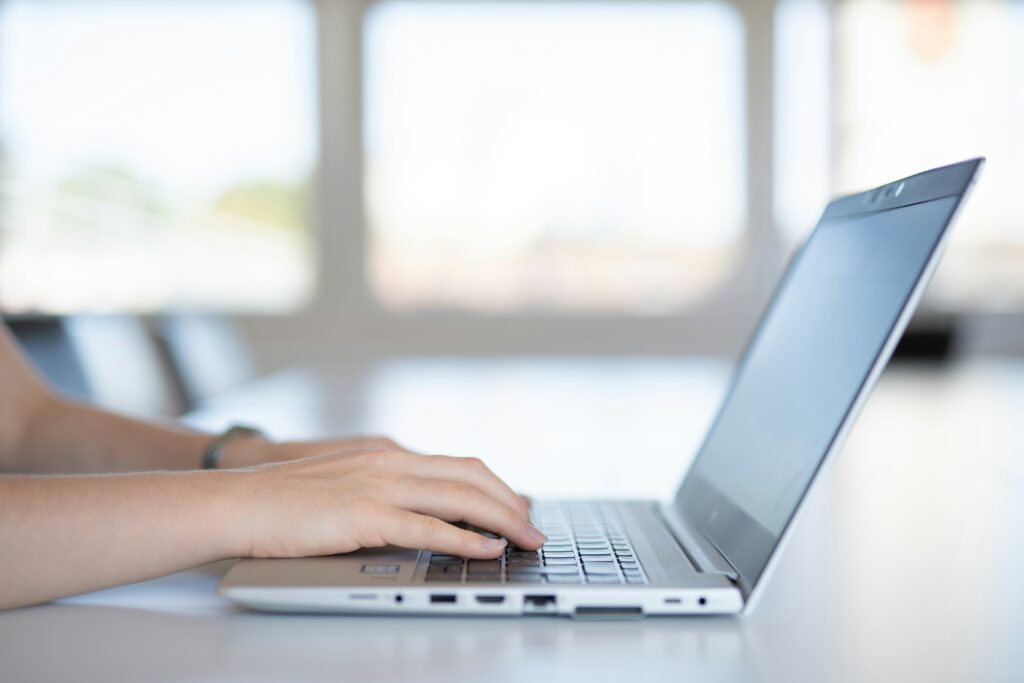 Close up shot of a person's hands as they type on a laptop